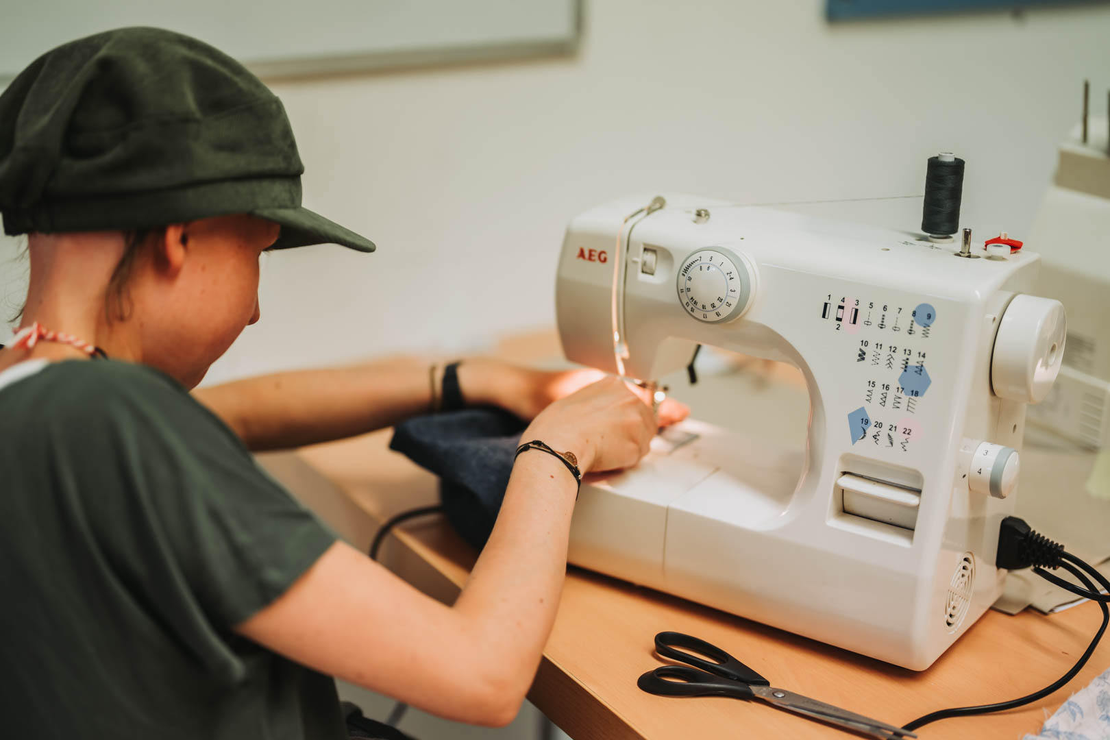 Eine Frau repariert an der Nähmaschine ein Kleidungsstück