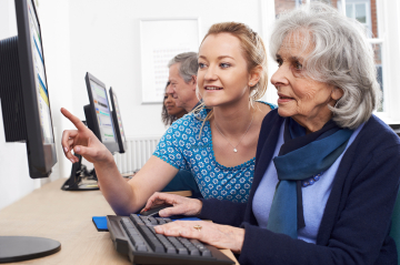 Zwei Personen sitzen vor dem Computer und erklären sich gegenseitig etwas.