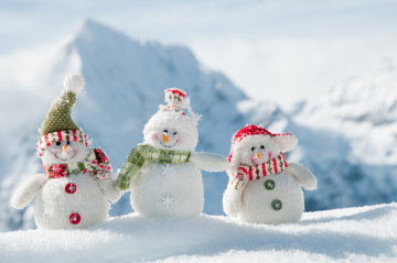 drei lachende Schneemänner mit bunter Winterkleidung, im Hintergrund eine Winterlandschaft