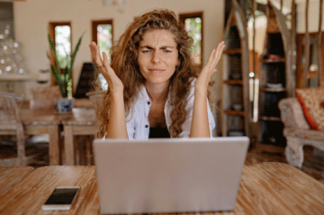 Eine Person sitzt fragend vor einem Laptop