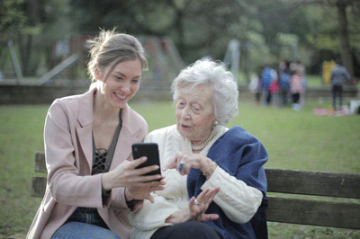 Eine junge Frau erklärt einer Seniorin etwas am Handy